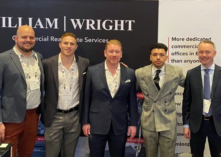 Commercial real estate brokers Patrick Wood, Connor Braid, Cory Wright, Nathan Armour, and Chris van Vliet pose in front of the William Wright Commercial booth at ICSC@Whistler held on March 27-29, 2022.