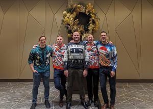 Commercial real estate experts Jeff Hassler, Connor Braid, Patrick Wood, Harry Jones, and Matthew Everitt in Christmas sweaters at the William Wright Commercial Christmas Party 2023
